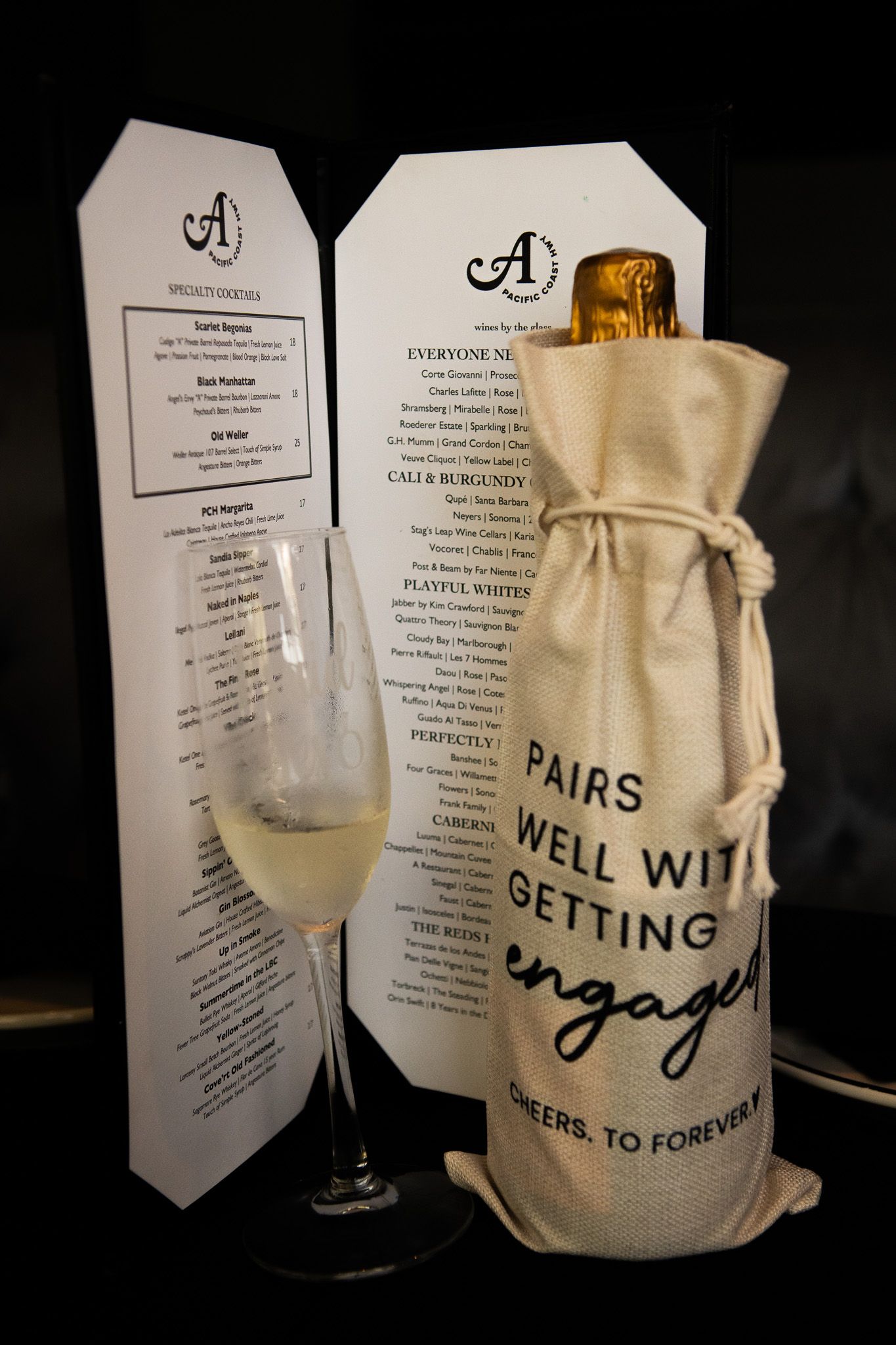 A series of restaurant menus and wine glasses displayed next to a decorative cloth bag.
