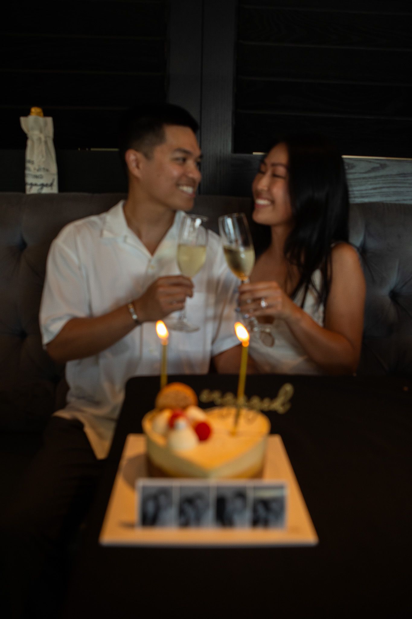 A romantic dinner scene with lit candles and a cake on a table in dim lighting.