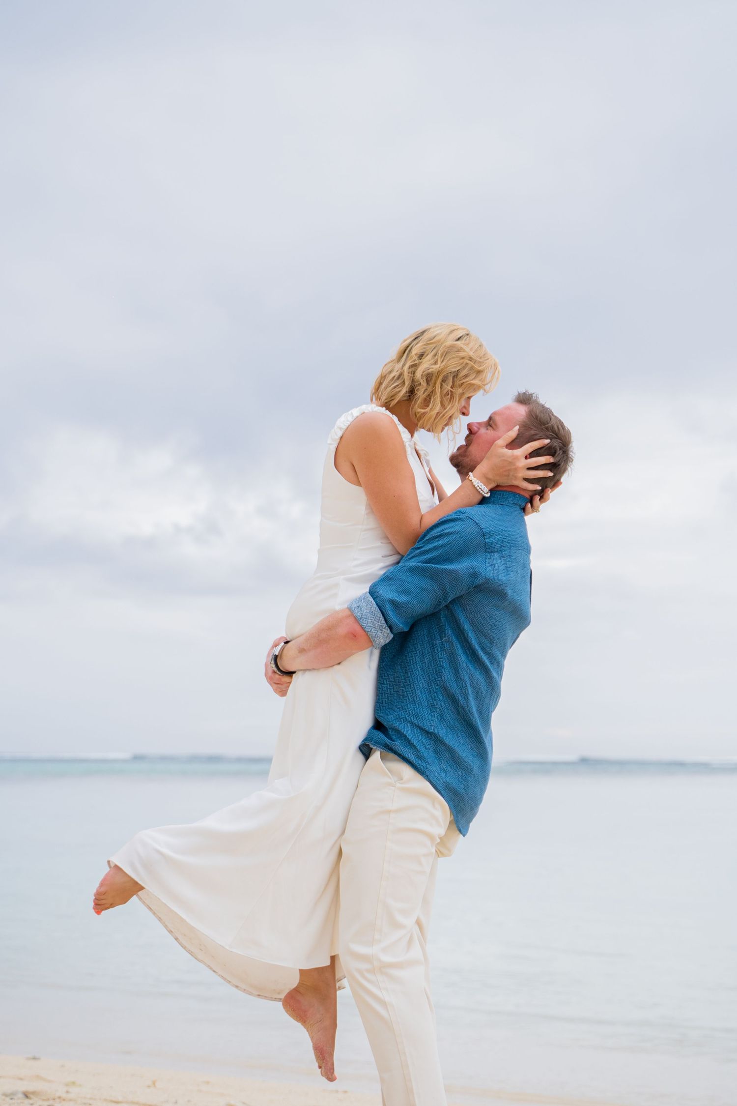 A romantic beach photoshoot with a couple in white outfits.