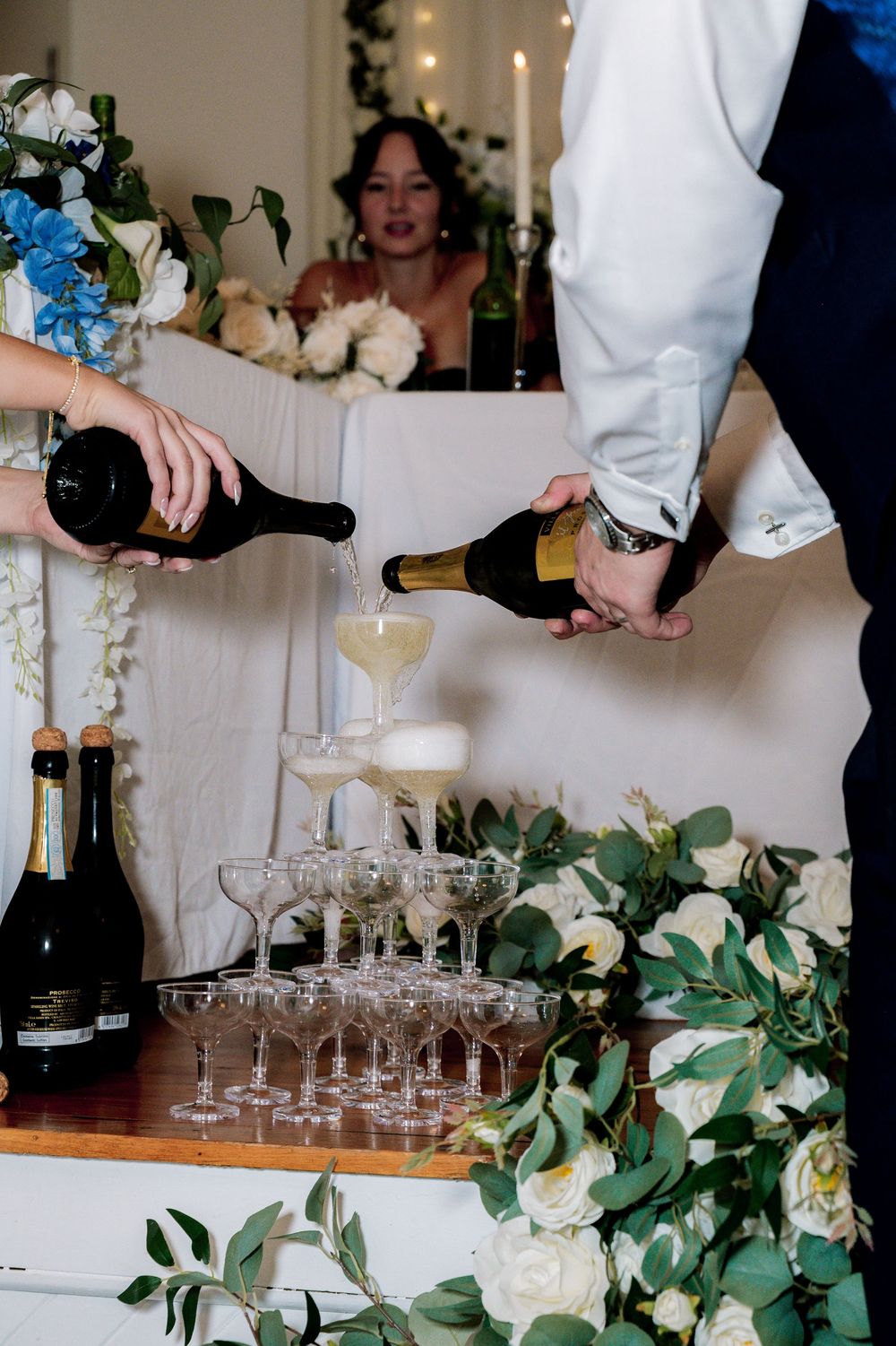 Champagne glasses being filled at an elegant event with greenery decorations on the table.