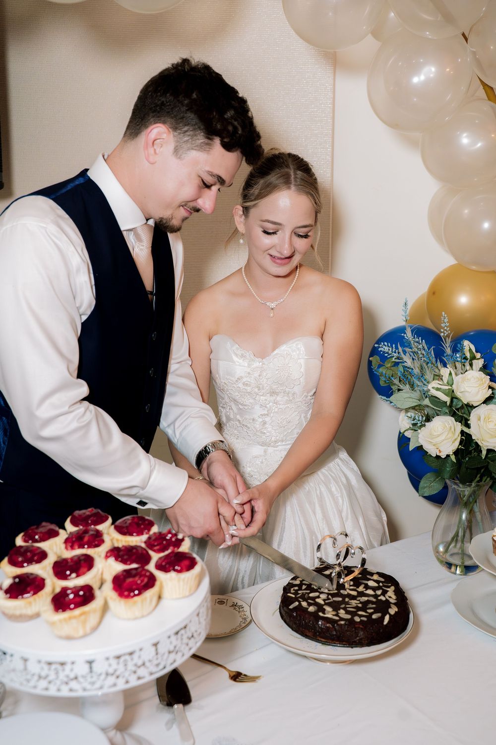 Wedding dessert table with raspberry cheesecakes and chocolate cake being served at a reception.