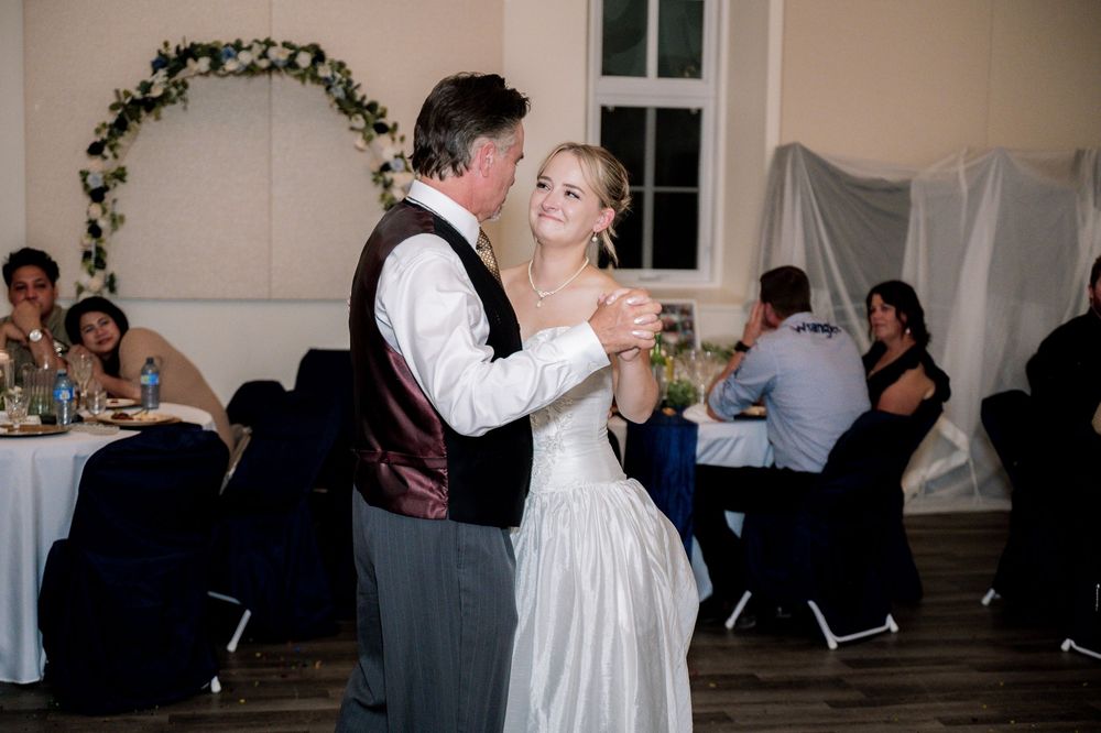 A couple dances in a romantic embrace during their wedding reception in a decorated church venue.