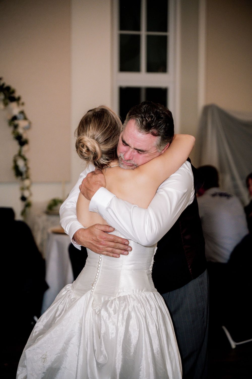 A tender embrace between newlyweds on their wedding day in a beautifully decorated reception venue.