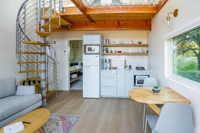 Modern loft apartment interior with spiral staircase, wood accents, and open concept living space showcasing minimalist design.