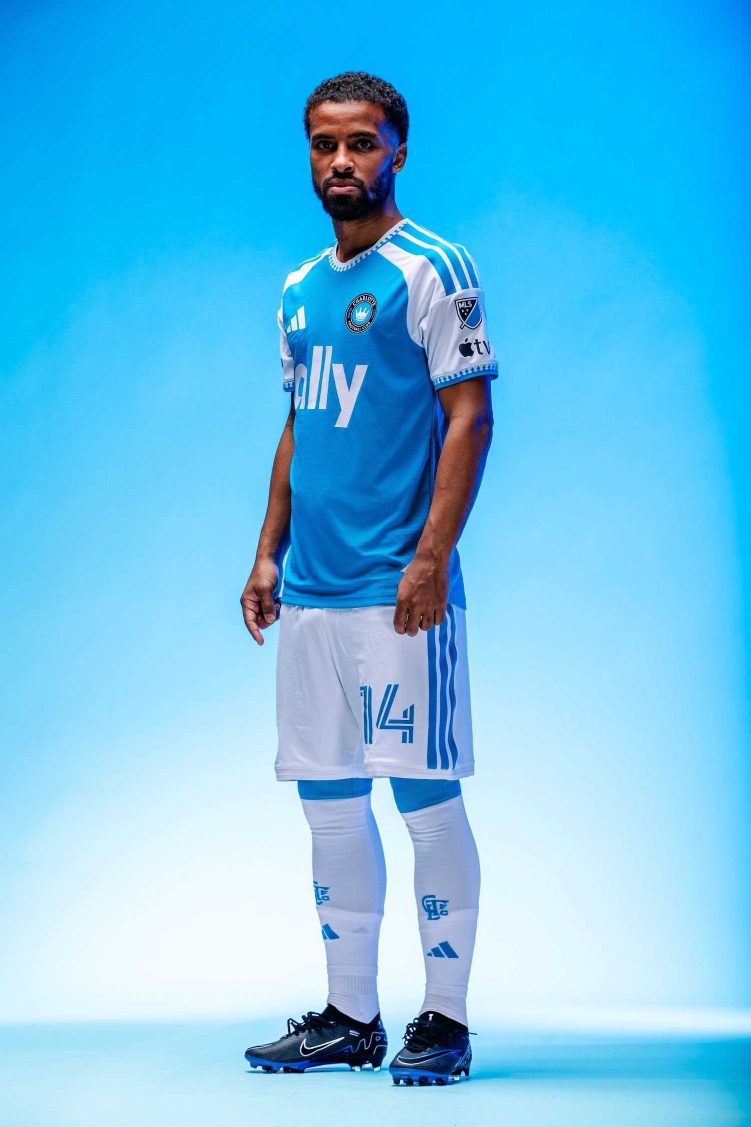 Charlotte FC player #14 stands in full blue Adidas ally kit with white shorts and Nike cleats.