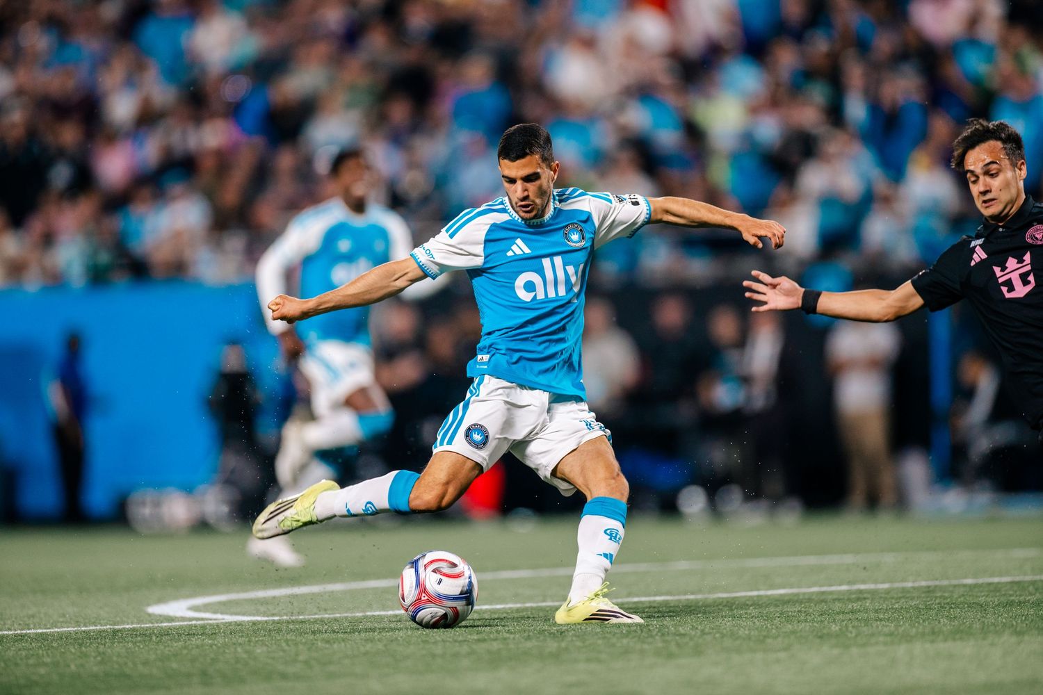 Charlotte FC player strikes ball in blue ally Adidas kit during competitive MLS game.