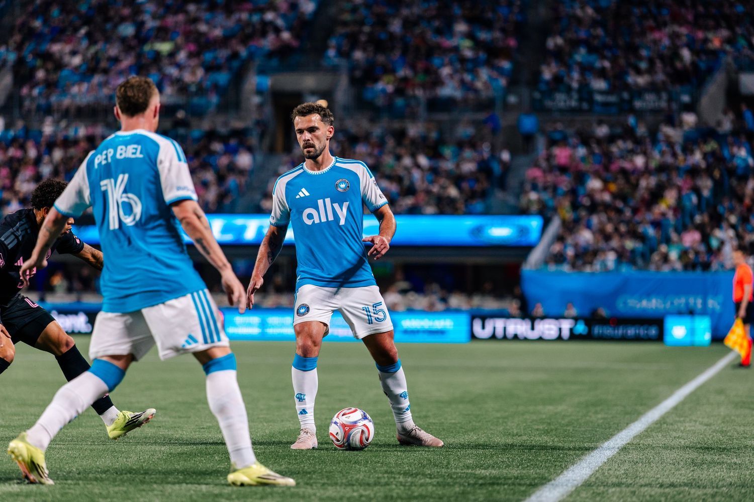 Charlotte FC players in blue ally jerseys set up play during MLS match at home stadium.