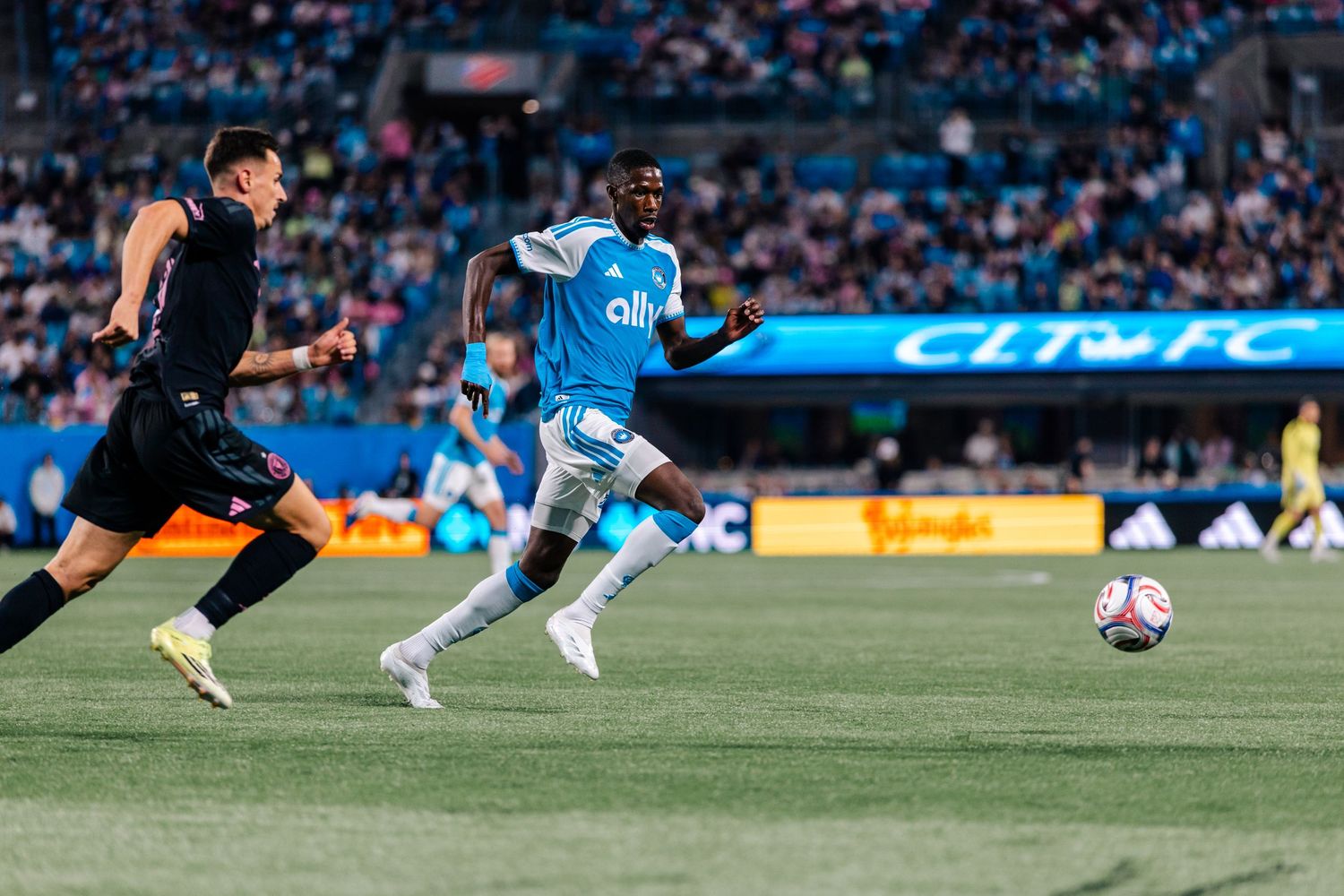 Charlotte FC player sprints in blue ally kit during fast-paced MLS match action.