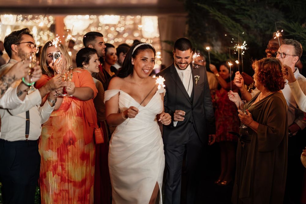 Wedding guests dance and celebrate on a dimly lit dance floor with warm lighting.