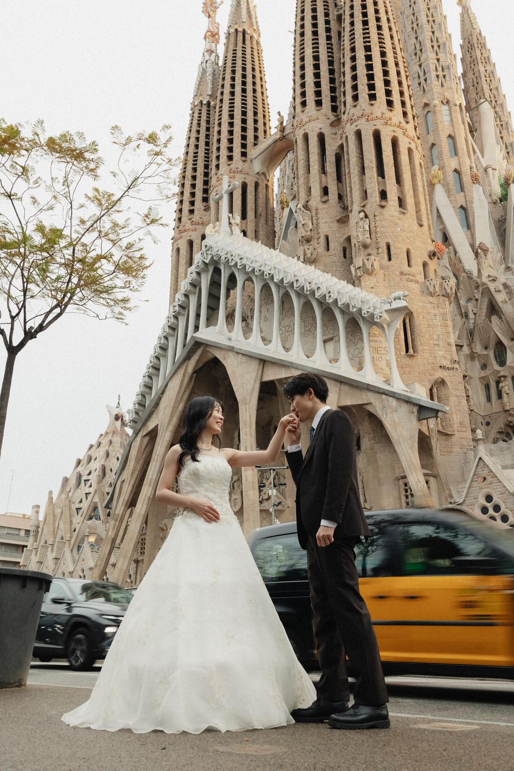 Wedding couple poses for photos in front of the iconic Sagrada Familia cathedral in Barcelona, Spain.