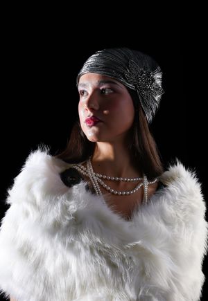Photo of a girl wearing a white shall, silver turban, and a pearl necklace, looking left