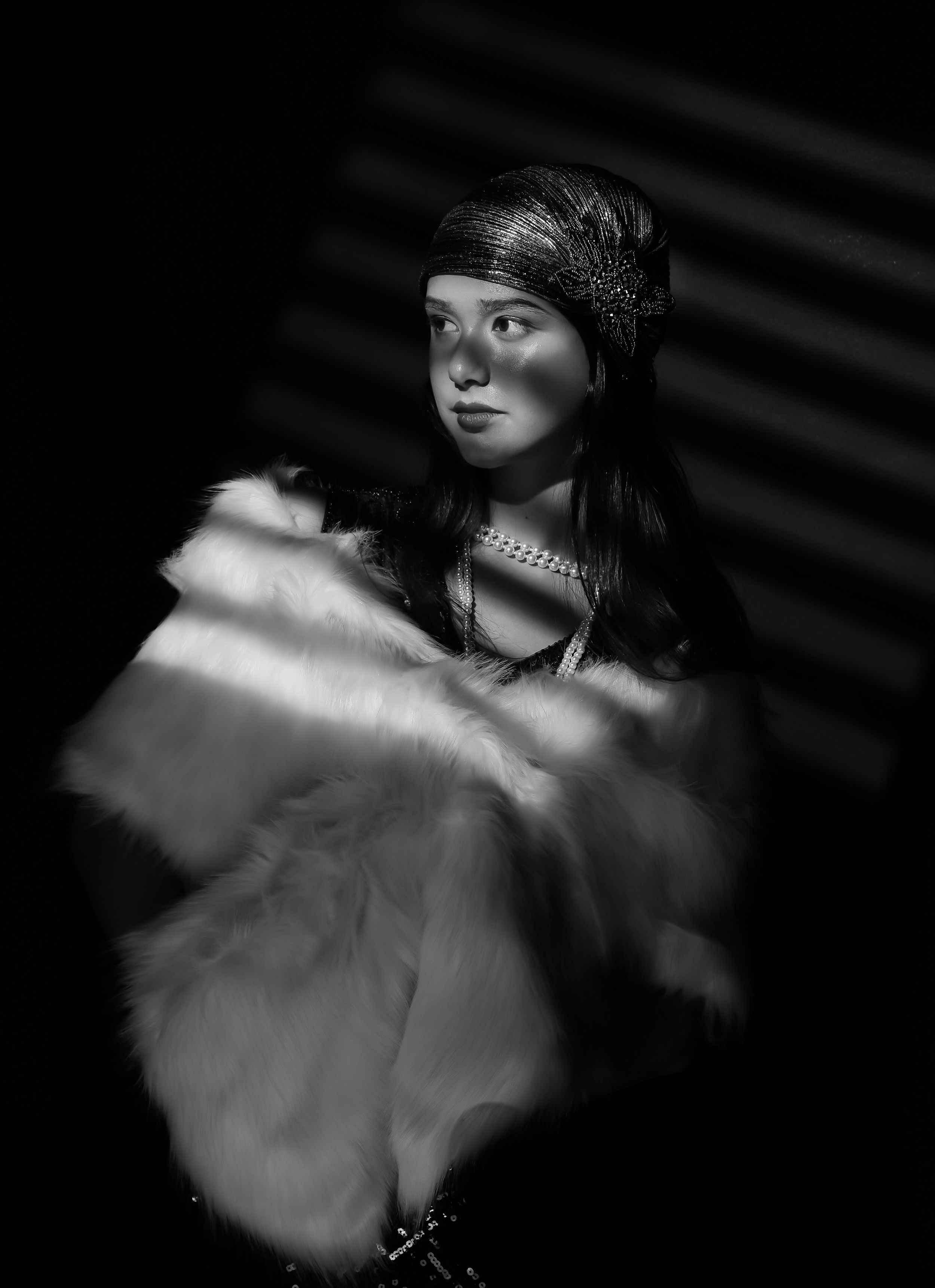Girl in blind like shadows, wearing a white shall, pearl necklace and a red flapper outfit, looking left, black and white