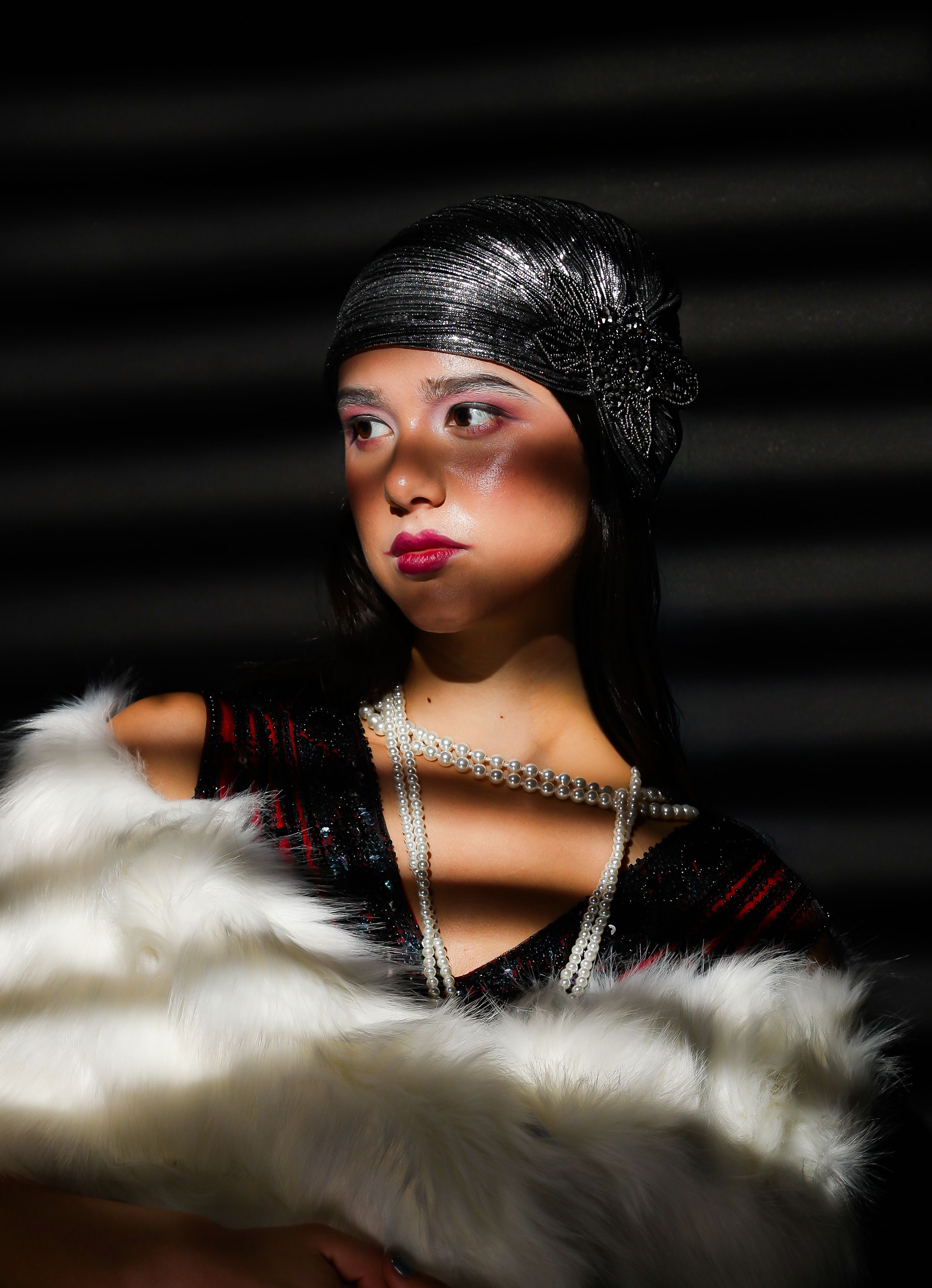 Girl in blind like shadows, wearing a white shall, pearl necklace and a red flapper outfit, looking left