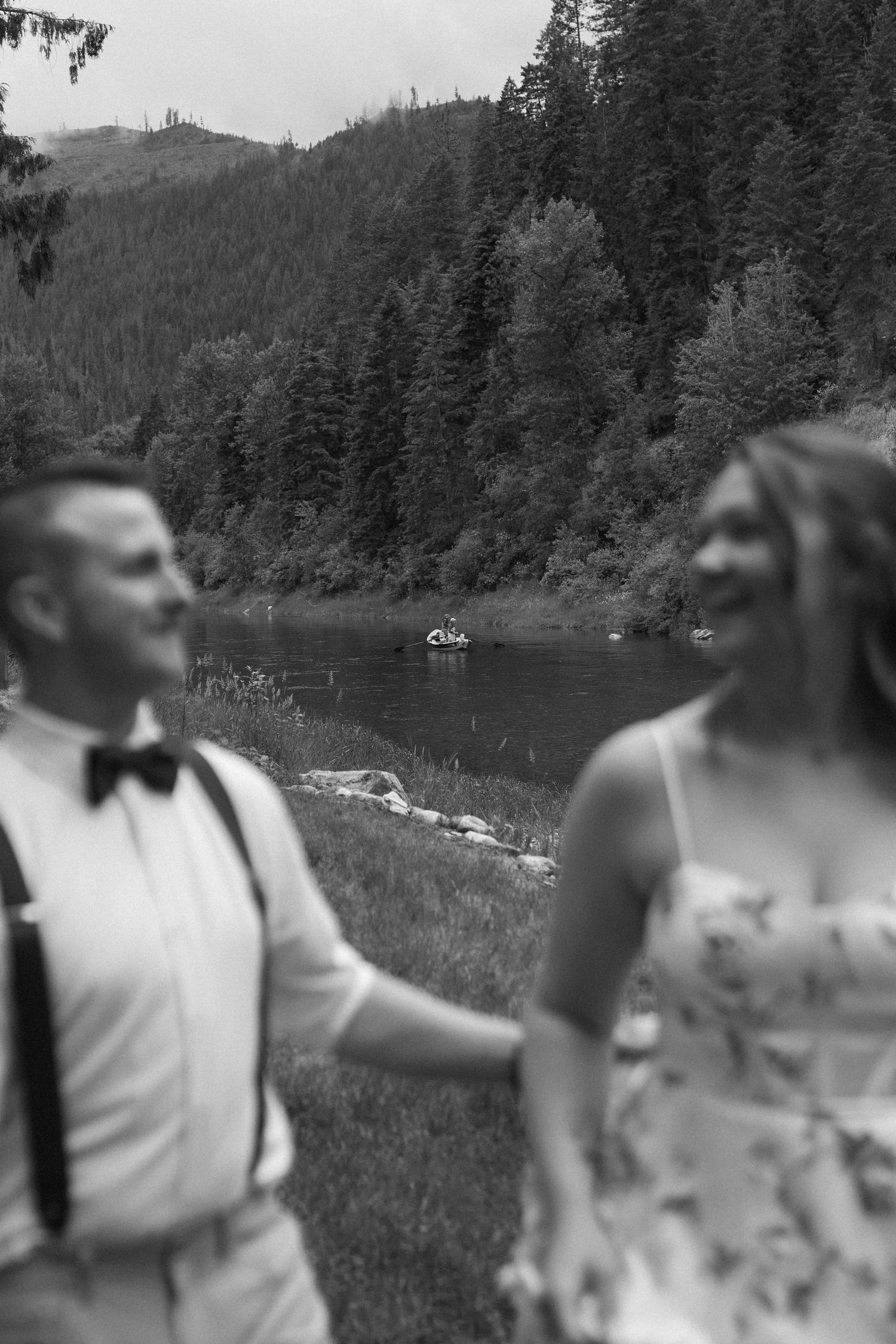 A group of people enjoying an outdoor gathering by a scenic mountain lake surrounded by evergreen forest.