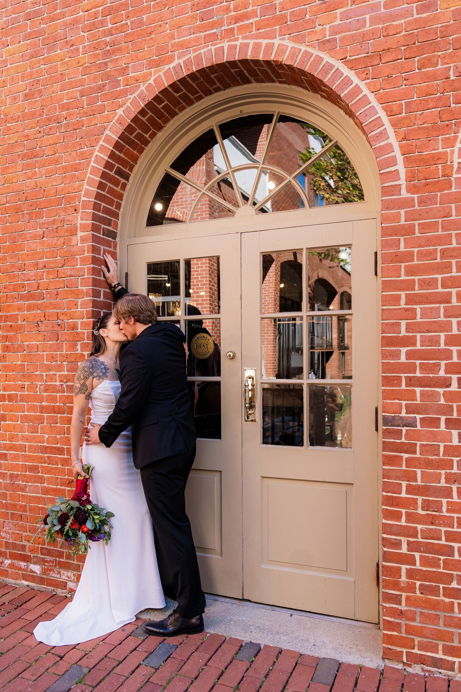 Eloping couple in front of a red brick building in Salem, Massachusetts after their intimate wedding ceremony.