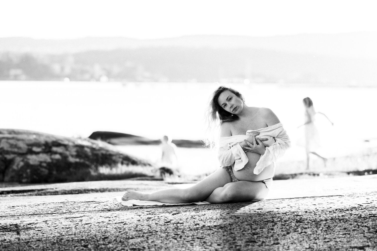 A person lies on a sandy beach in a relaxed pose near the ocean during sunset.