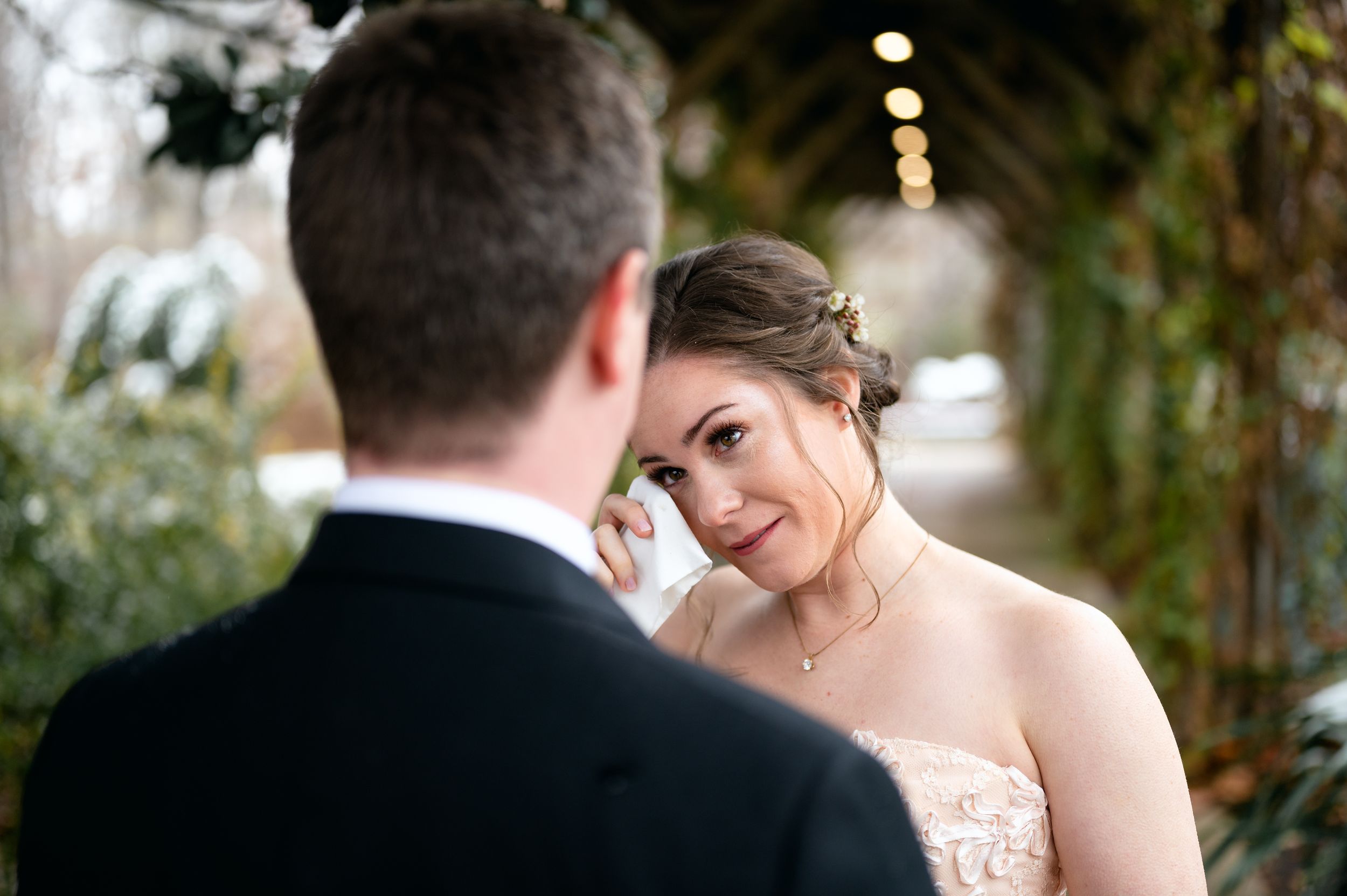 A romantic wedding couple shares intimate moments in a garden setting with soft lighting and natural greenery.