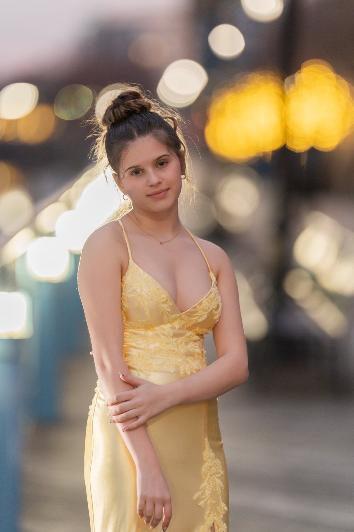 Night portrait of Ava in a yellow prom dress with city lights glowing at the Wilmington Riverfront.