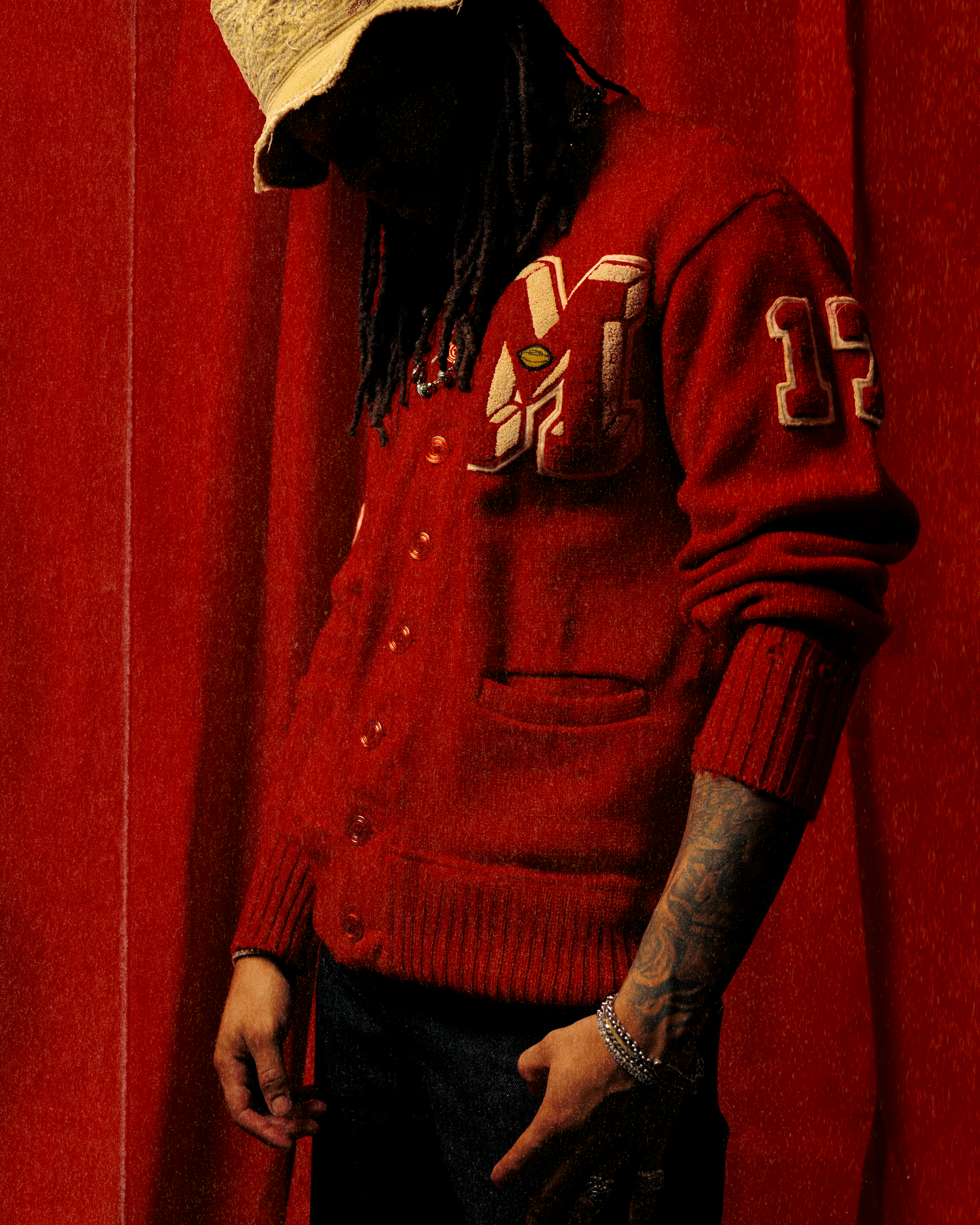 A group wearing red sweaters and uniforms stands in front of a red curtain background.