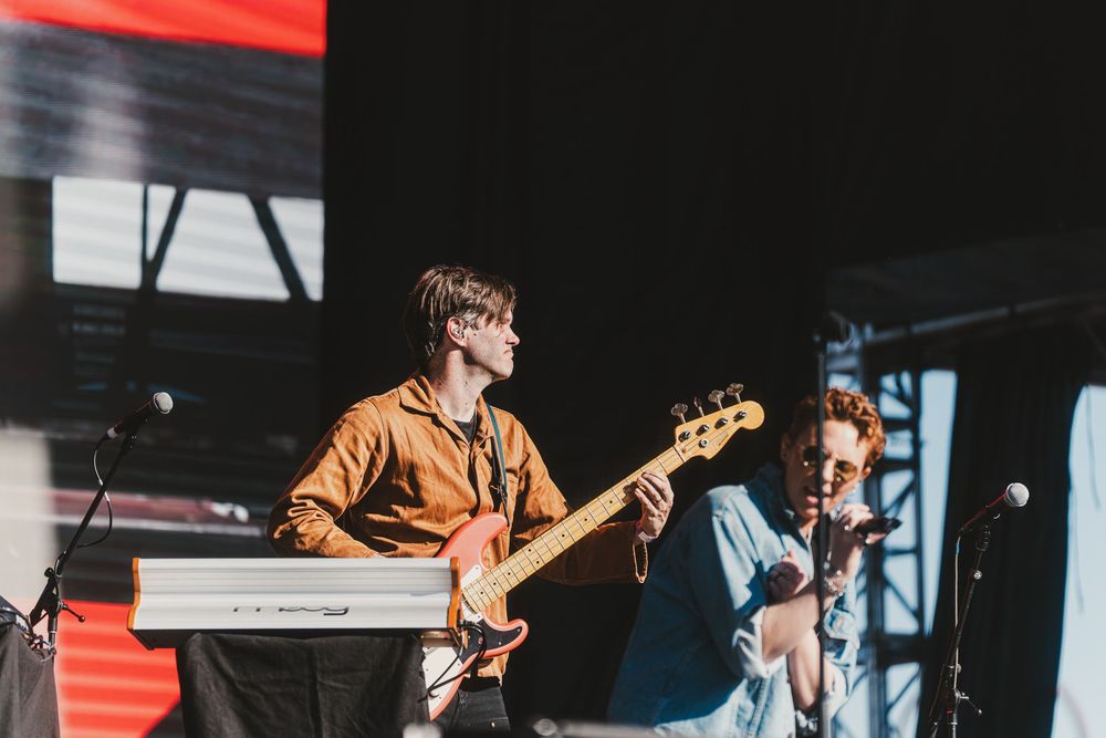 Musicians perform on stage with guitars and microphones during a live concert performance.