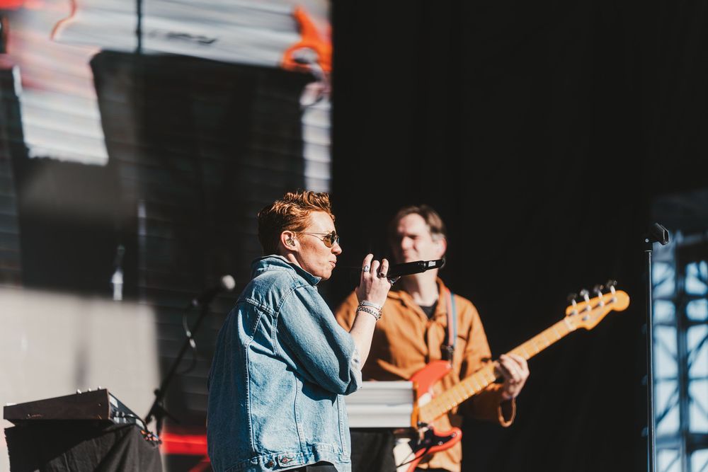 Musicians perform together on stage during a live concert with guitars and microphones.