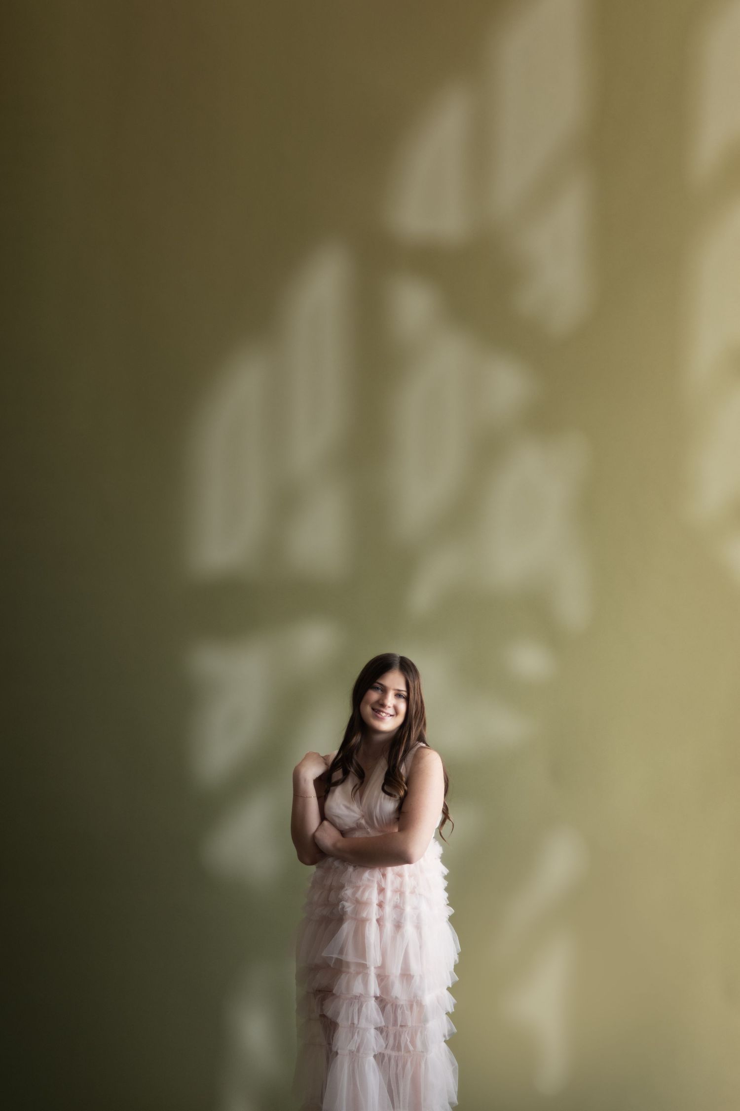 A dreamy portrait series showing a person in a light pink ruffled dress against a soft green background.