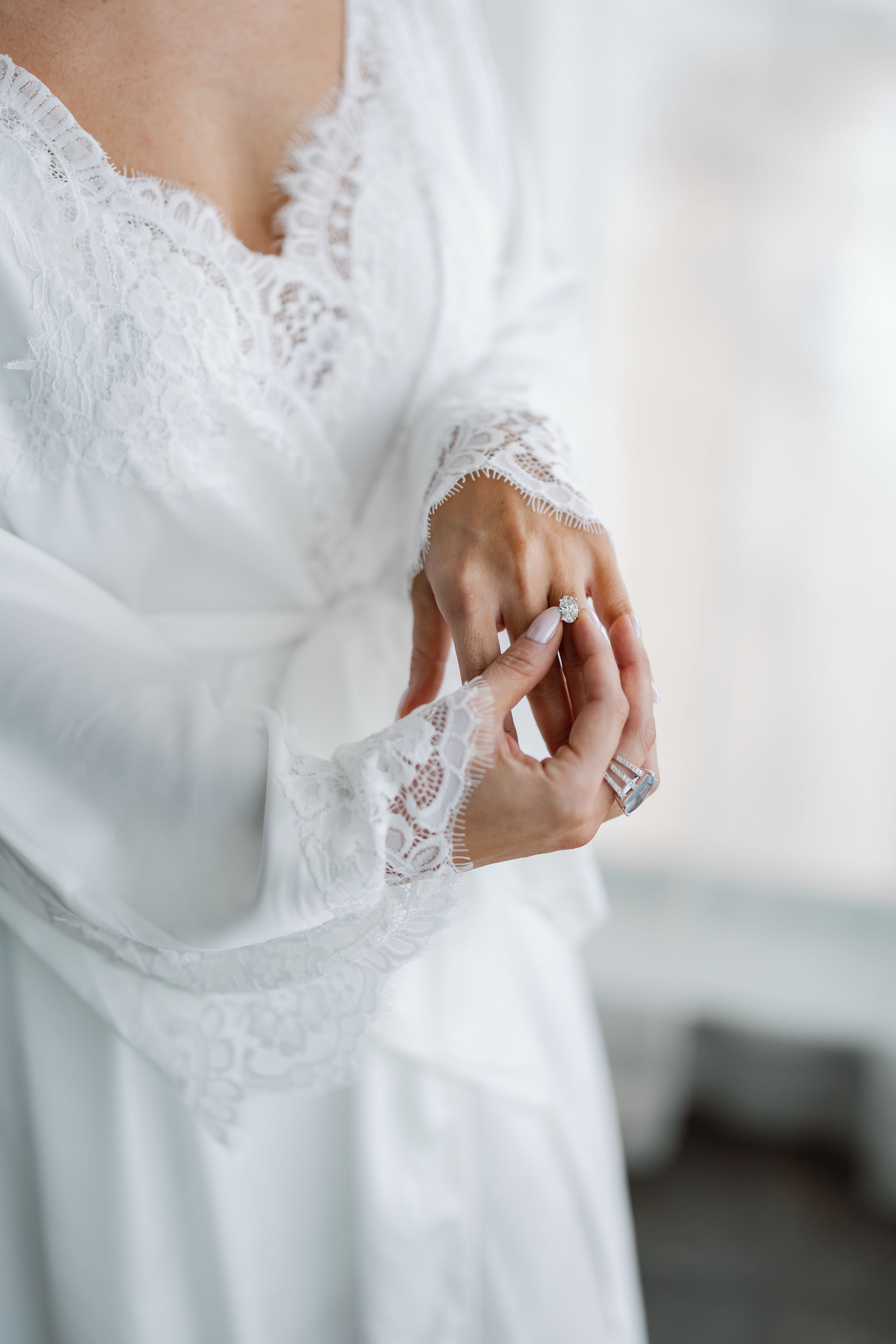 A close-up view of a woman's hand adjusting the lace on her wedding dress.