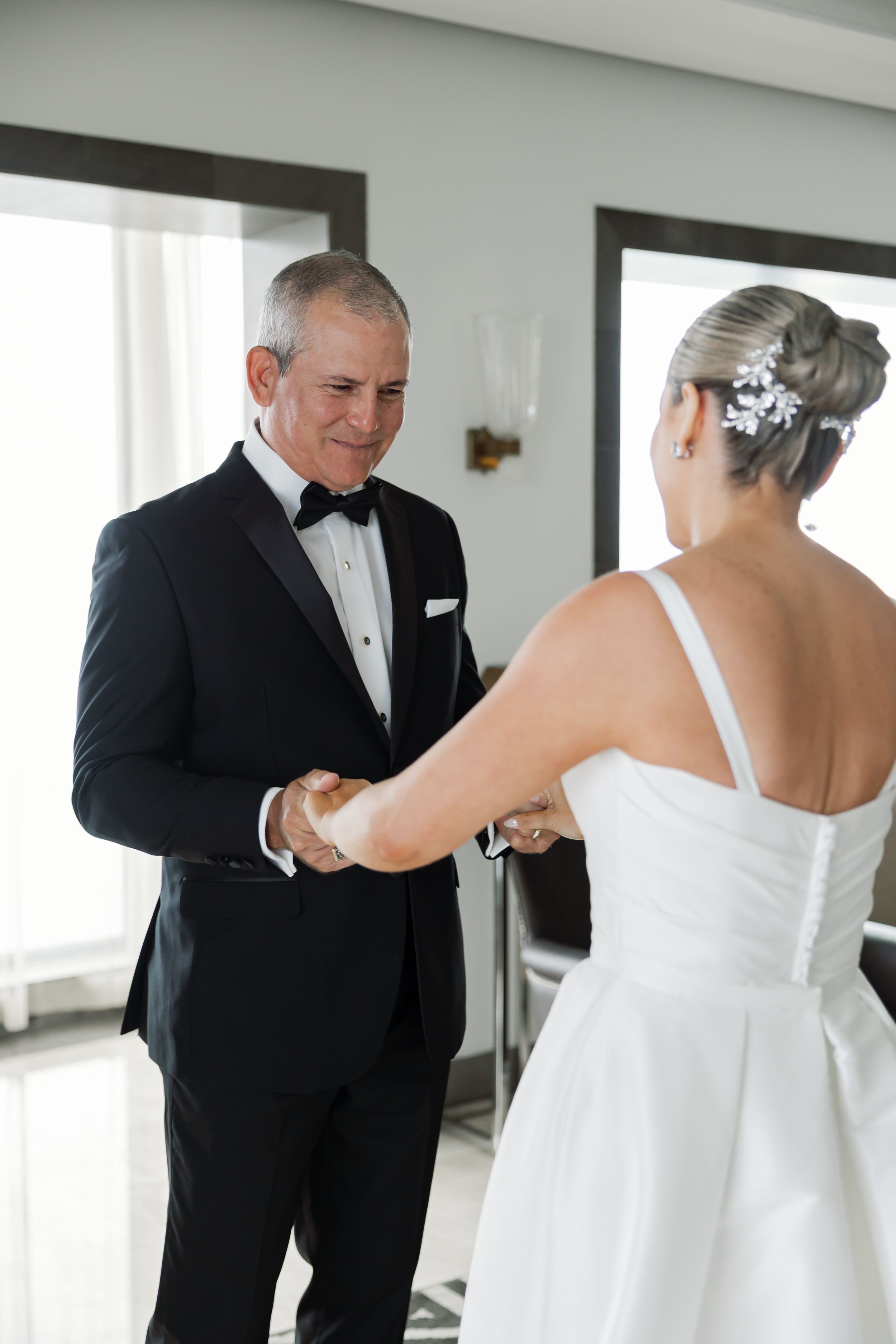 A man in a tuxedo and a woman in a white wedding dress are shown shaking hands.