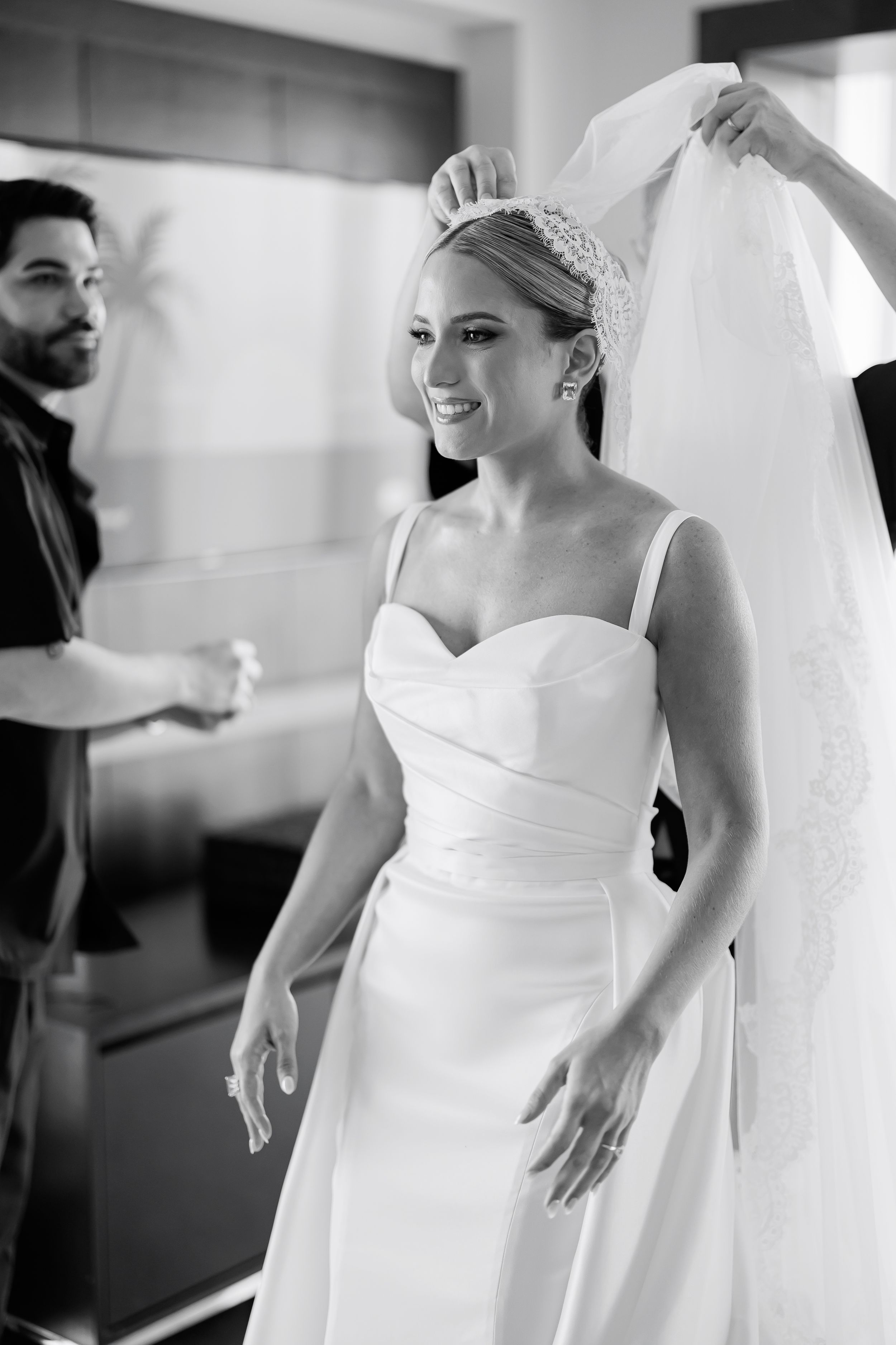 A man in a tuxedo and a woman in a white wedding dress are shown together in a room.