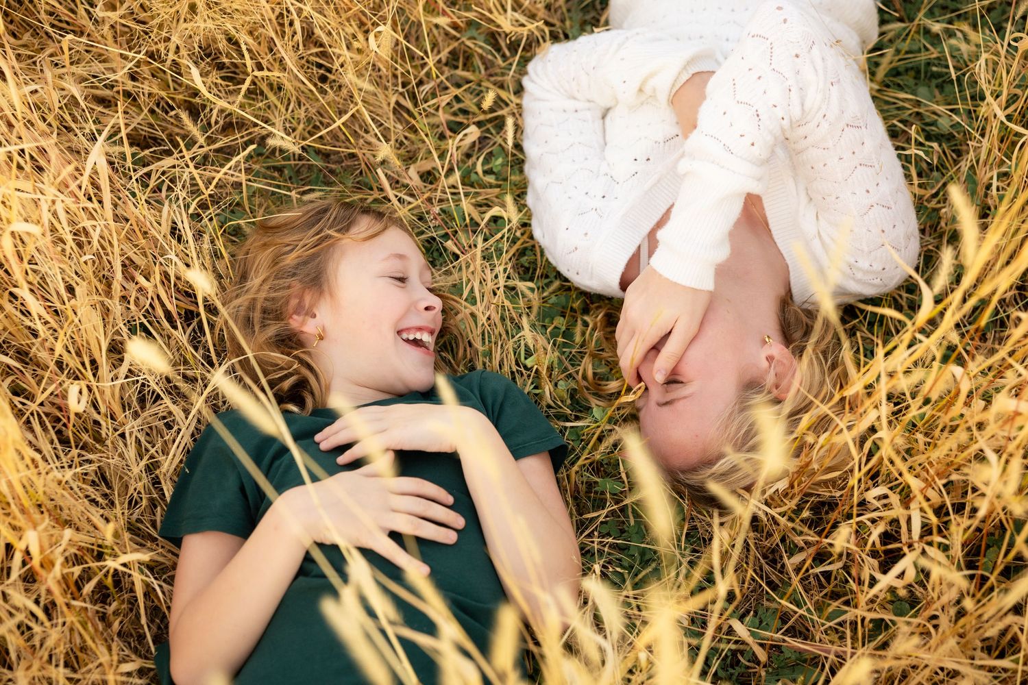 A couple lies in golden wheat field sharing intimate moments during a romantic outdoor photoshoot.