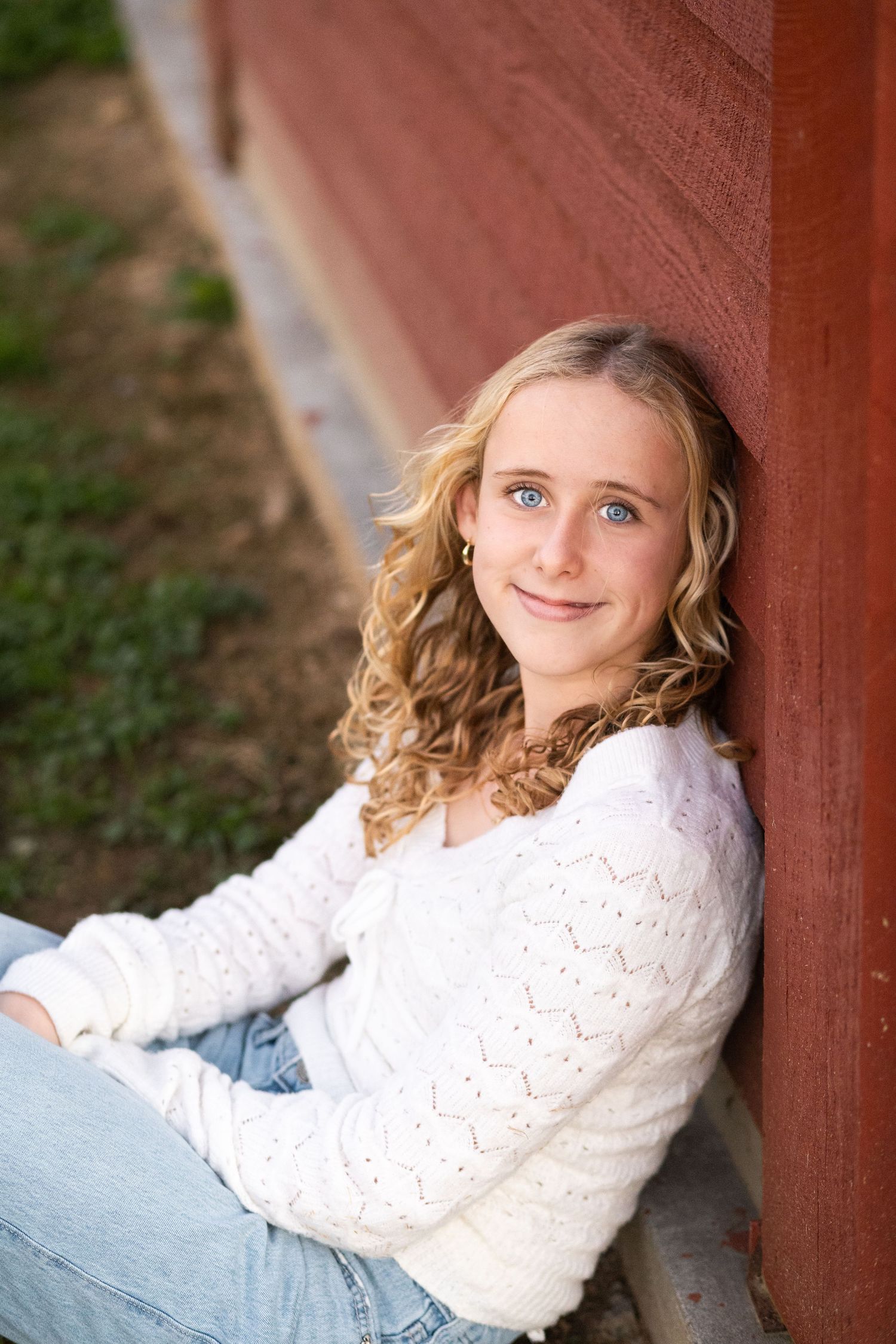 A series of portrait photos showing someone in a white sweater and jeans leaning against a red wooden structure outdoors.