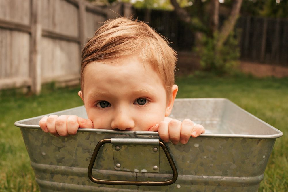 Curious toddler peeking over the edge of a metal tub during milk bath session | Broomfield Family Photographer