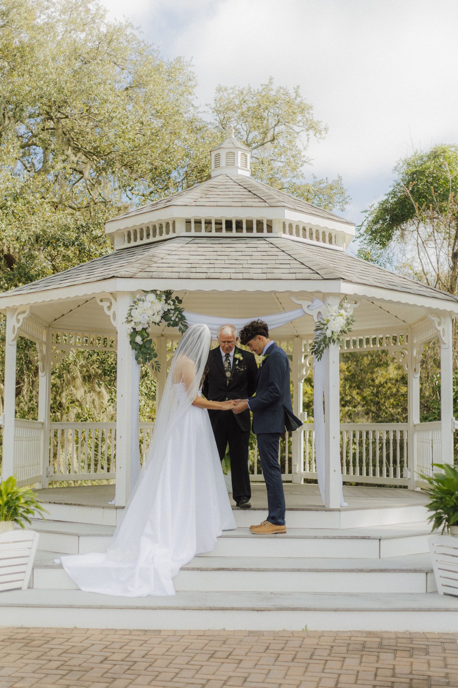 A white wedding gazebo ceremony setup with elegant decor and natural surroundings.