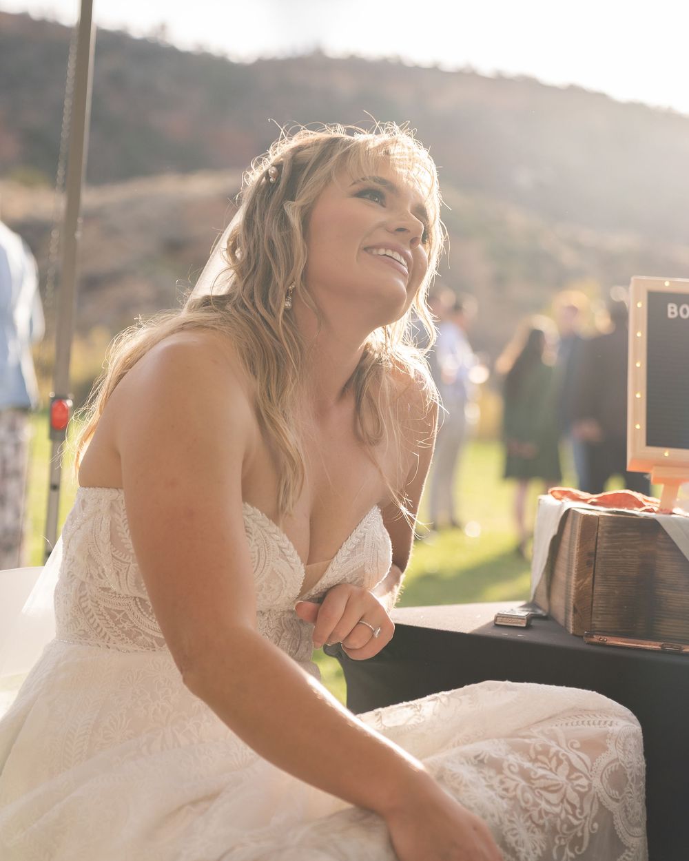A bride in a white lace wedding dress laughs joyfully during an outdoor celebration at sunset in Rockville, Utah