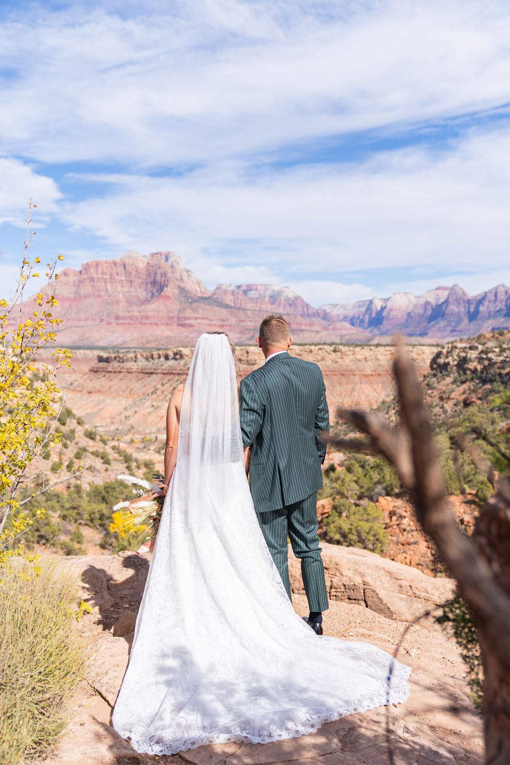 A couple stands together overlooking the majestic red rock formations and desert landscape at Zion National Park.