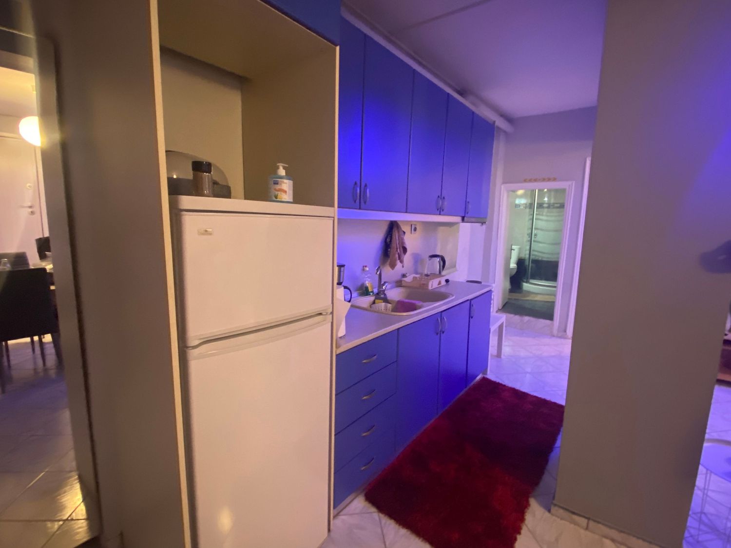 Modern hallway with purple LED accent lighting and white walls features a dramatic red carpet runner.