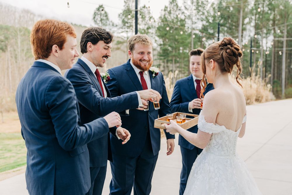 A group in formal attire sharing appetizers and drinks during an outdoor wedding celebration.