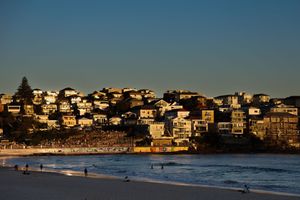 Bondi Beach as the sun sets creating a golden glow over the buildings