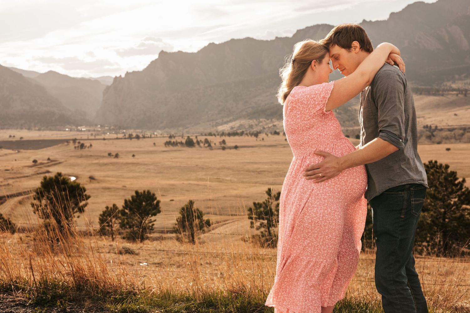 ouple embracing during golden hour maternity session with scenic mountain valley backdrop | Maternity Photos in Boulder Colorado