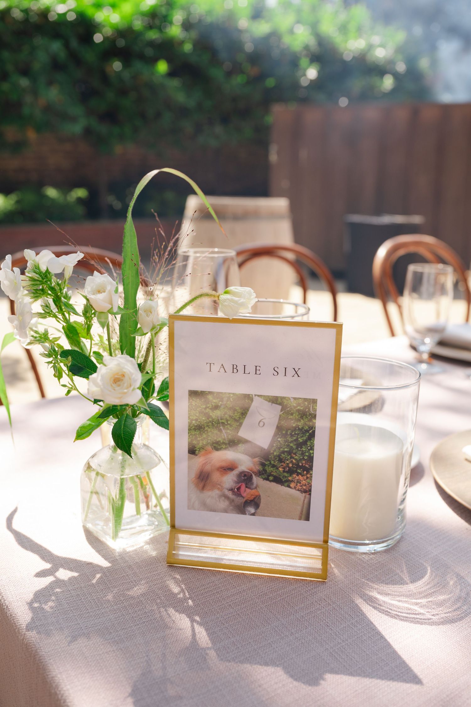 Elegant wedding reception table settings with framed photos, candles, and white linens create an intimate dining atmosphere.