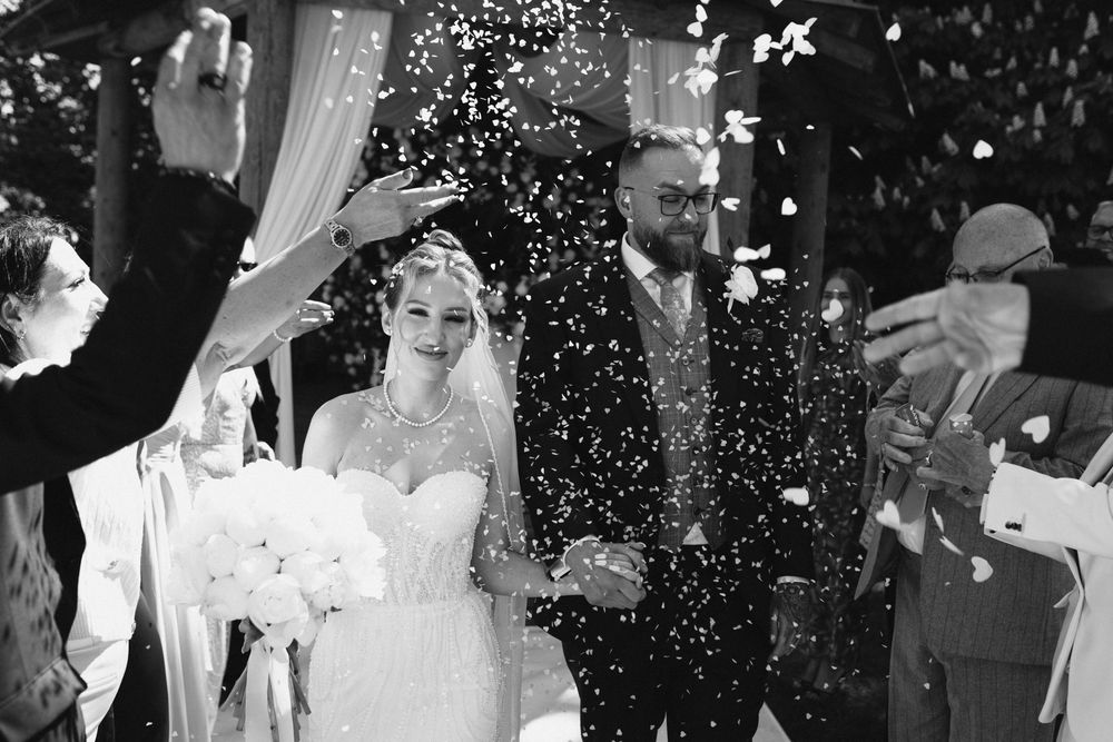 A couple dances together at their wedding reception under twinkling lights and falling confetti.