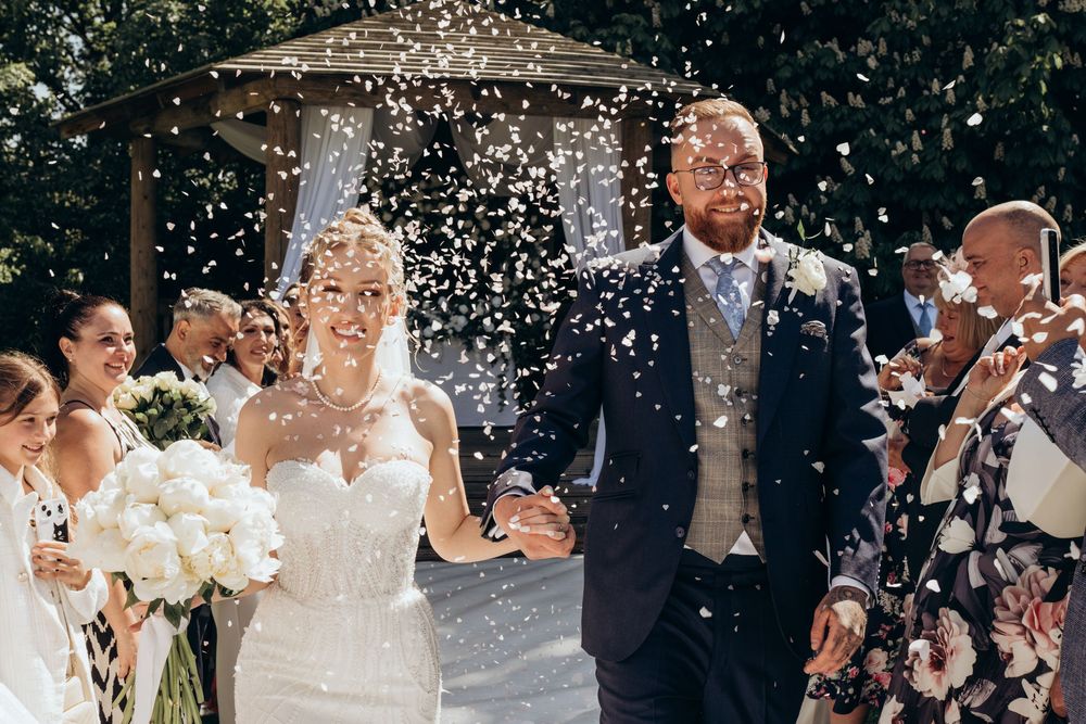 Wedding party celebrates with confetti and laughter during an outdoor celebration in a joyful moment.