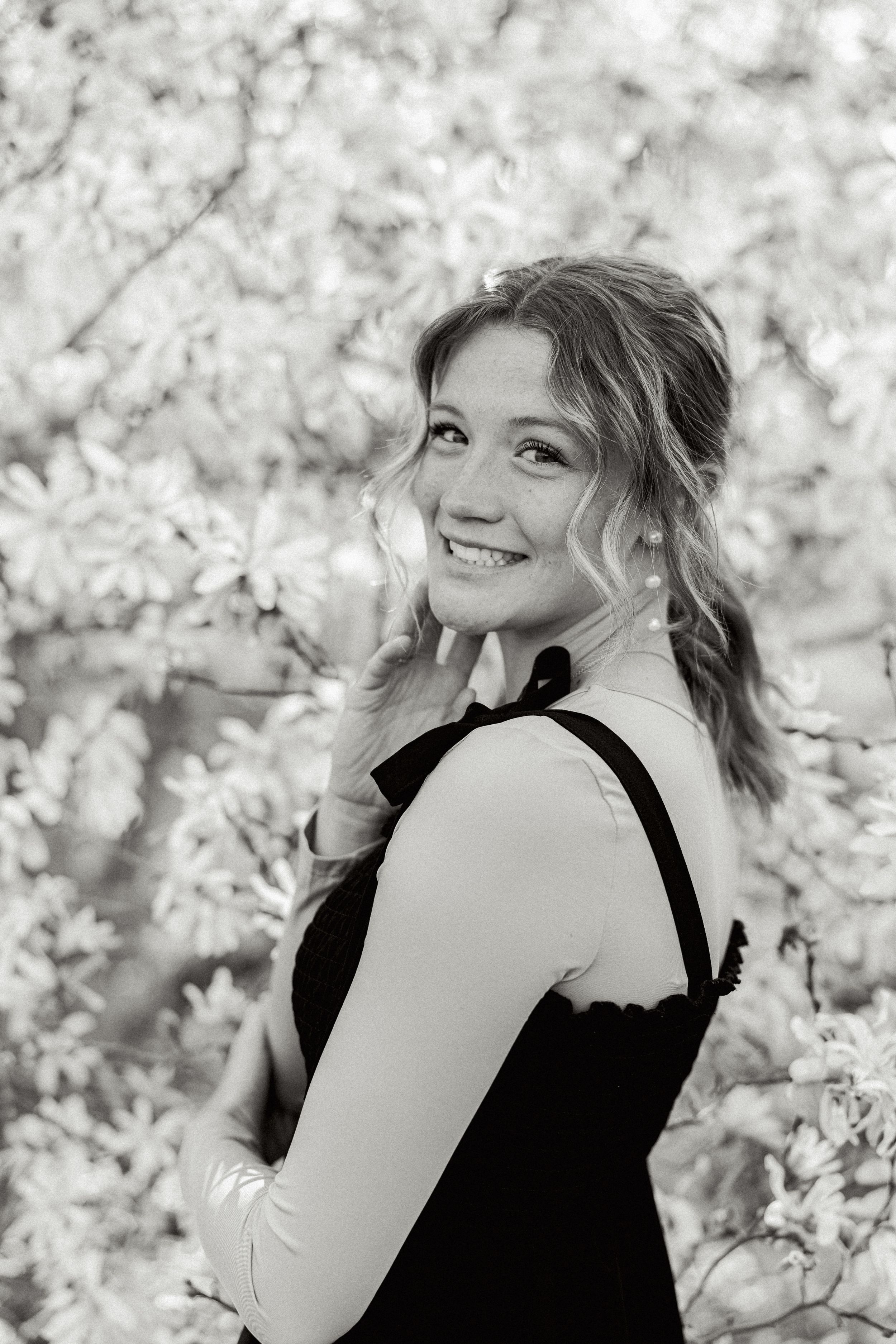 Black and white portrait series among spring blossoms showing joyful expressions and natural poses.
