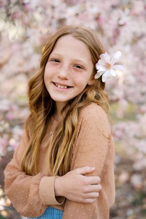 A springtime portrait series featuring someone in a peach-colored sweater among pink cherry blossoms.