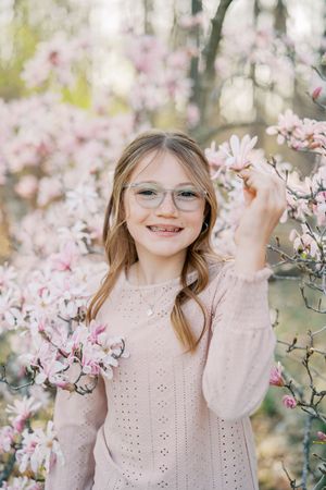 A series of springtime portraits amid blooming pink magnolia trees with soft natural lighting and a delicate eyelet dress.