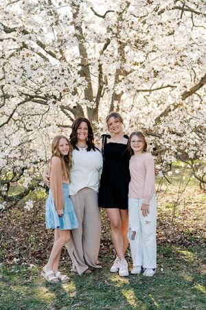 A group poses together under blooming cherry blossom trees on a sunny spring day.