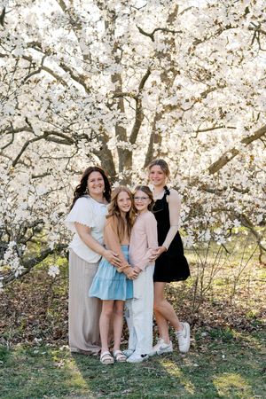 Group portrait under blooming white cherry blossom trees in spring garden setting.