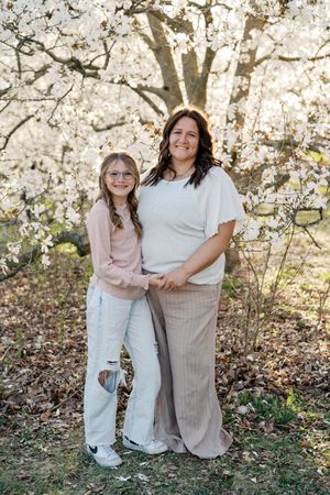 A casual outdoor portrait session with people wearing pastel and neutral clothing among spring blossoms.