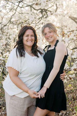 Candid outdoor photoshoot featuring casual white and black outfits against blooming spring trees.