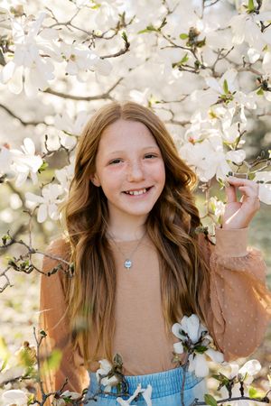 Joyful spring portrait surrounded by delicate white cherry blossoms in natural light.